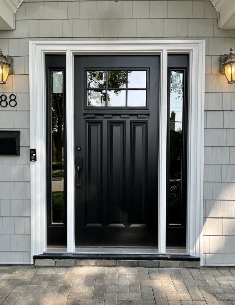 Black front door with sidelights, white trim, and gray siding.