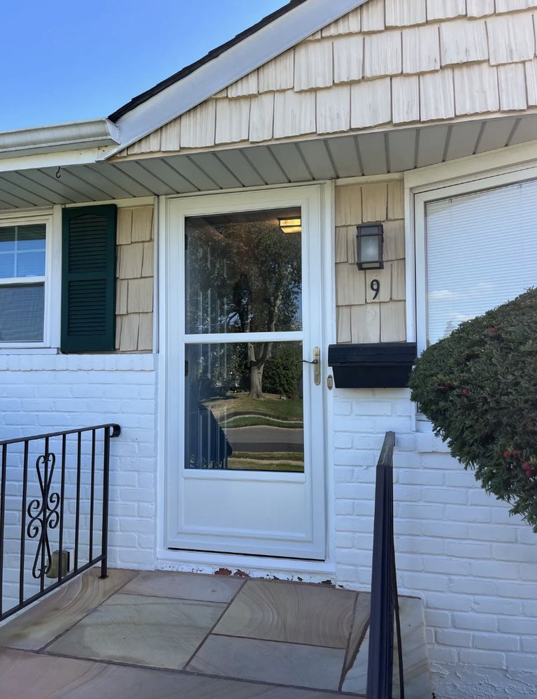 White door of house with number 9, brick facade, black mailbox, and railing.