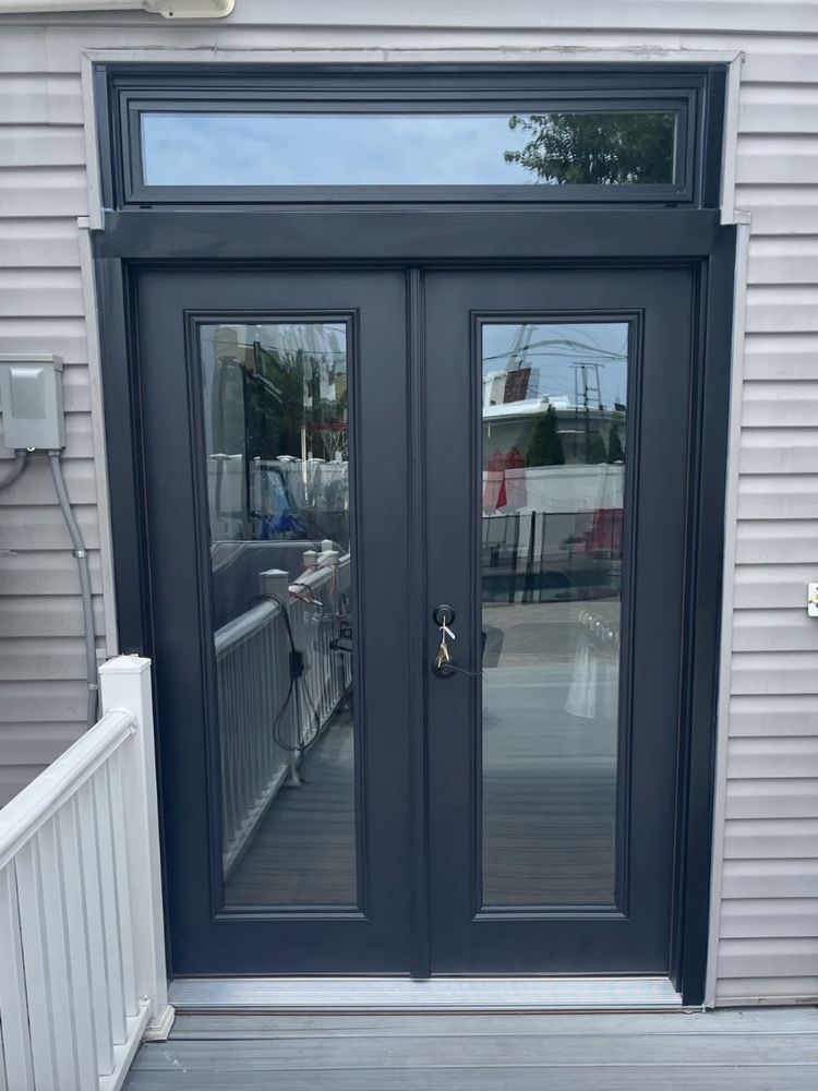 Dark double doors with glass panels, above them a glass window. Outside on a patio.