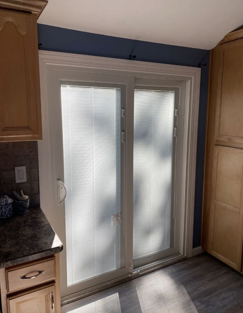 Kitchen with a sliding glass door covered by blinds. Sunlight streams in. Blue wall.