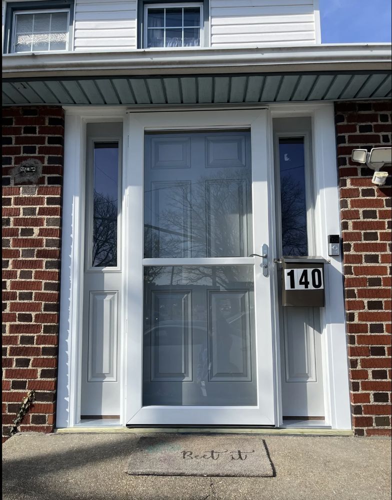 Front door of a brick house with white trim, storm door, and address 140 on the mailbox.