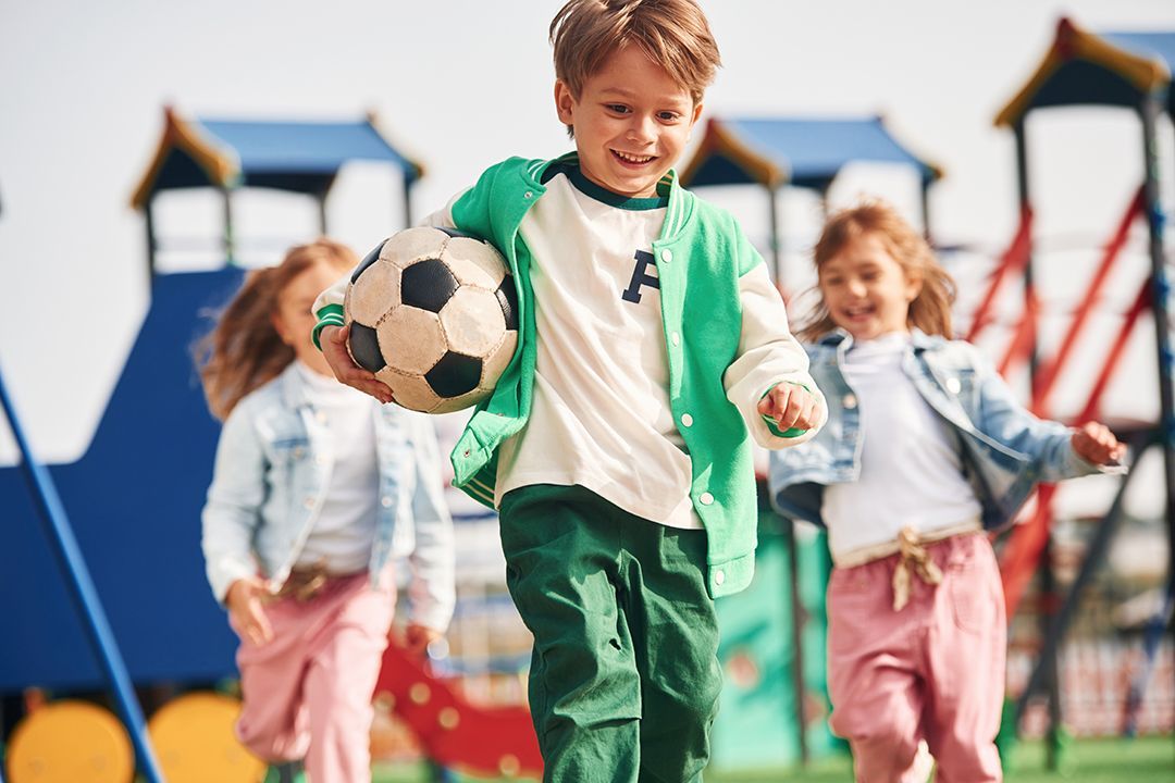 A group of children are playing with a soccer ball in a playground.