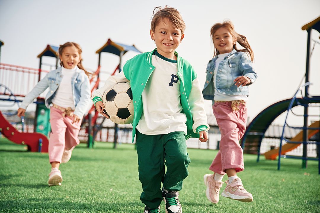 A group of children are playing with a soccer ball in a playground.