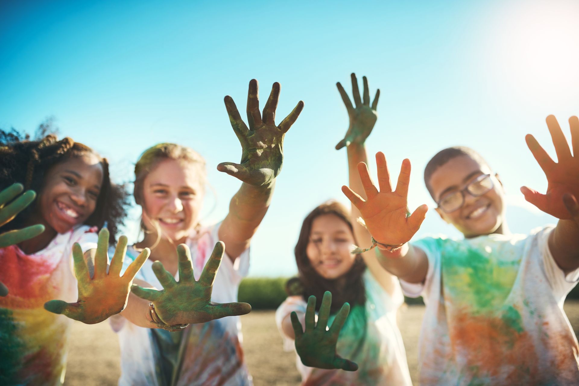 A group of children are holding their hands up in the air.