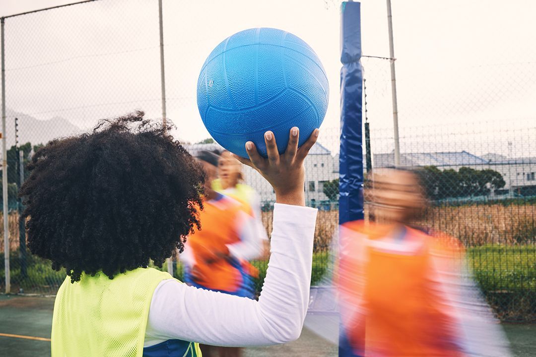 A person is holding a blue ball in their hand on a basketball court.