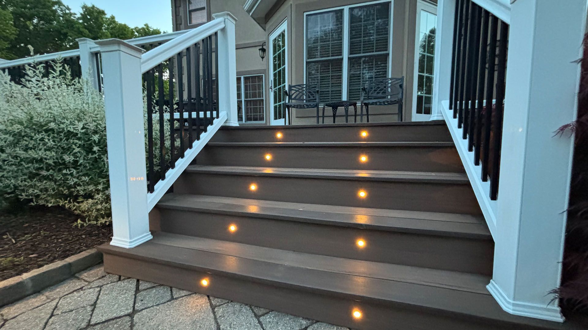 A deck with stairs leading up to it and lights on the steps.