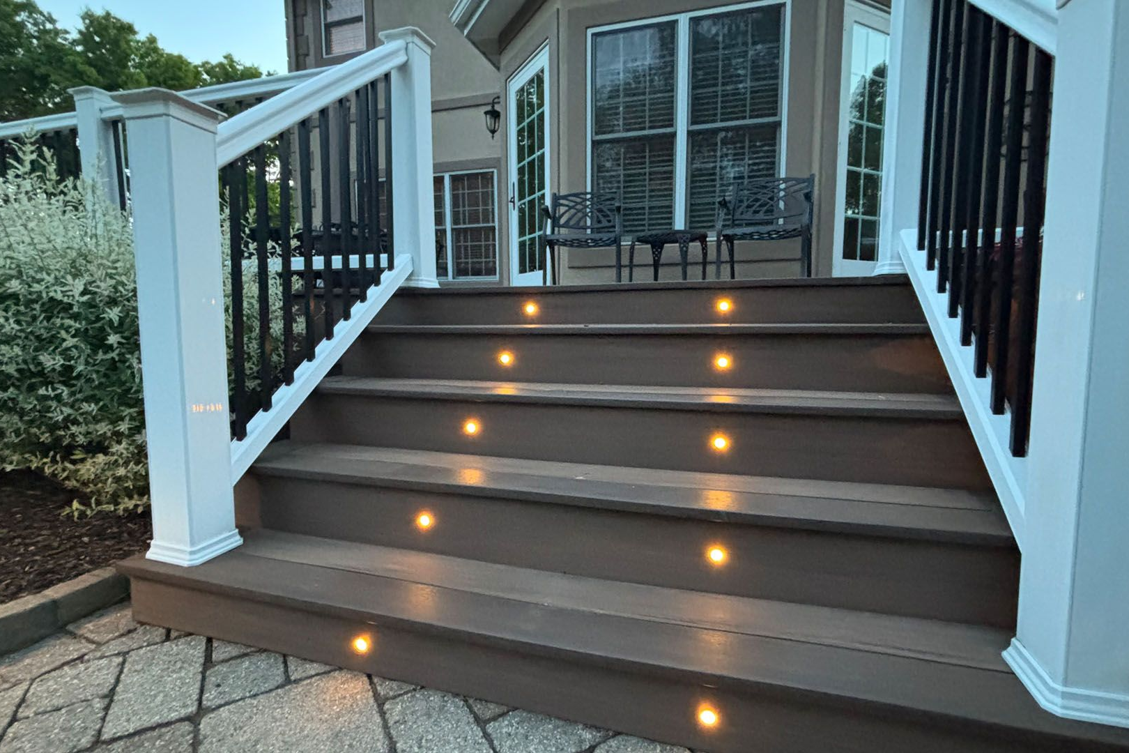 A deck with stairs leading up to it and lights on the steps.