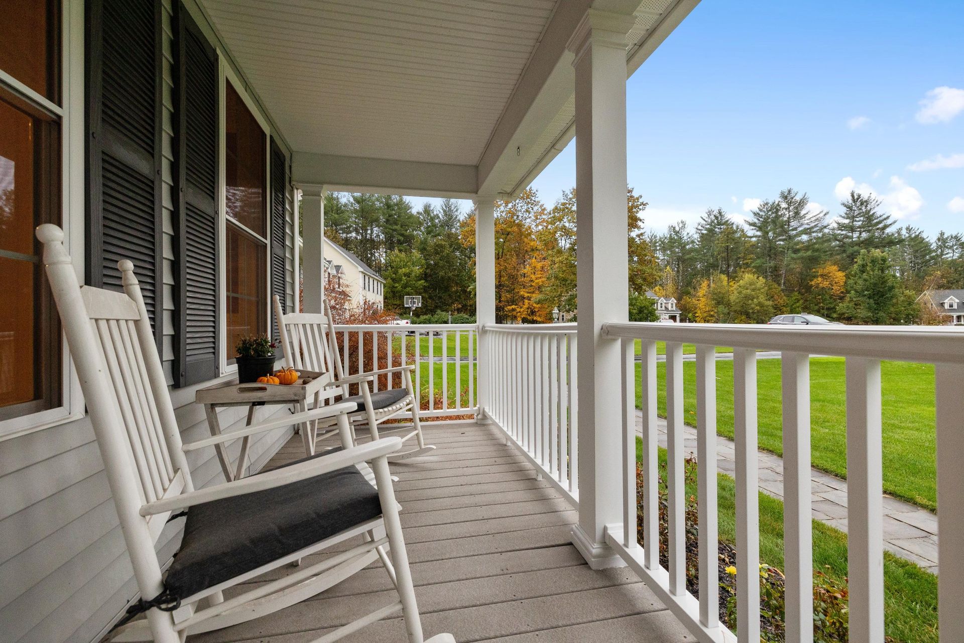 There are two rocking chairs on the porch of a house.