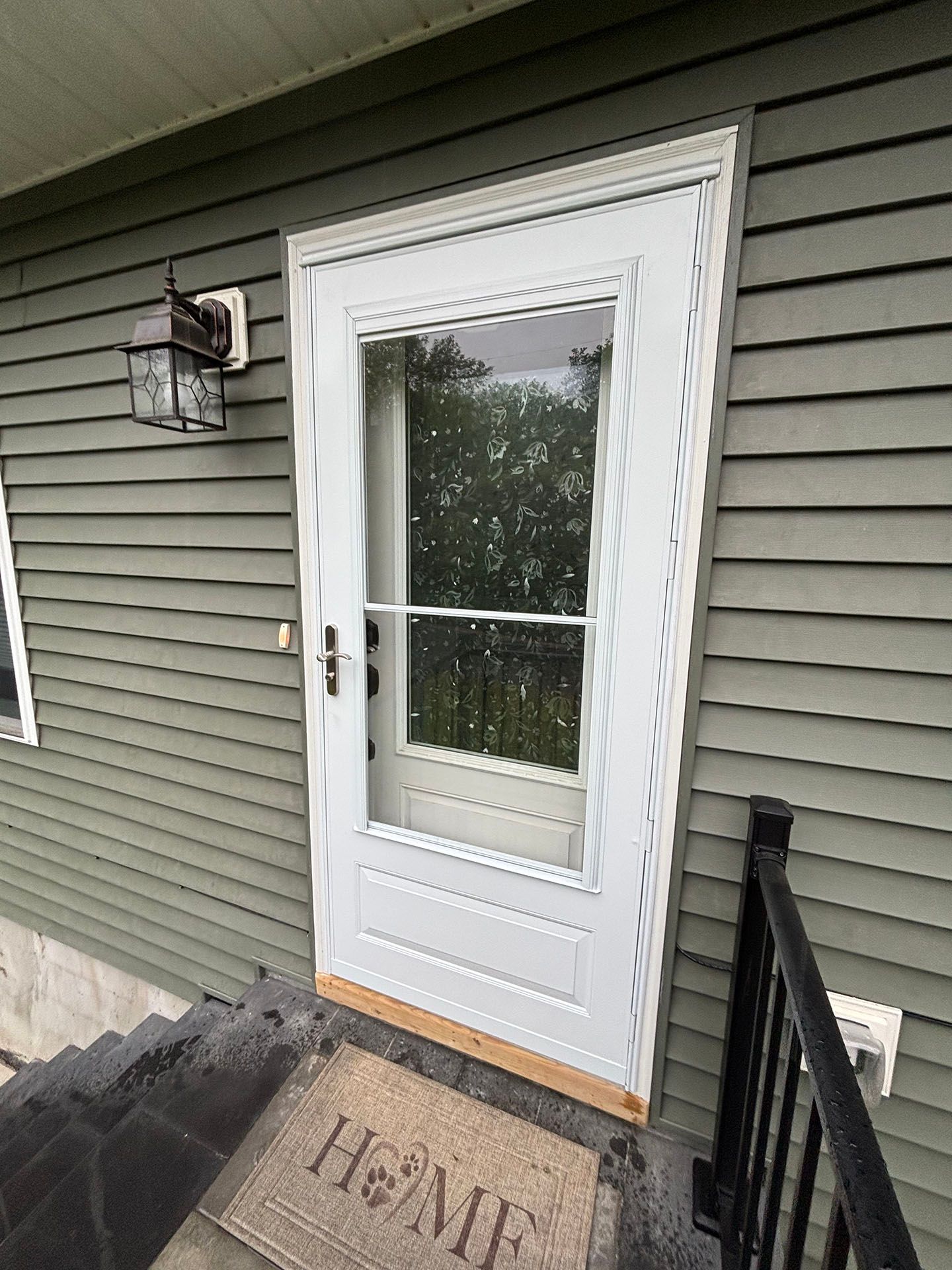 A white door with a window and a welcome mat on the steps of a house.