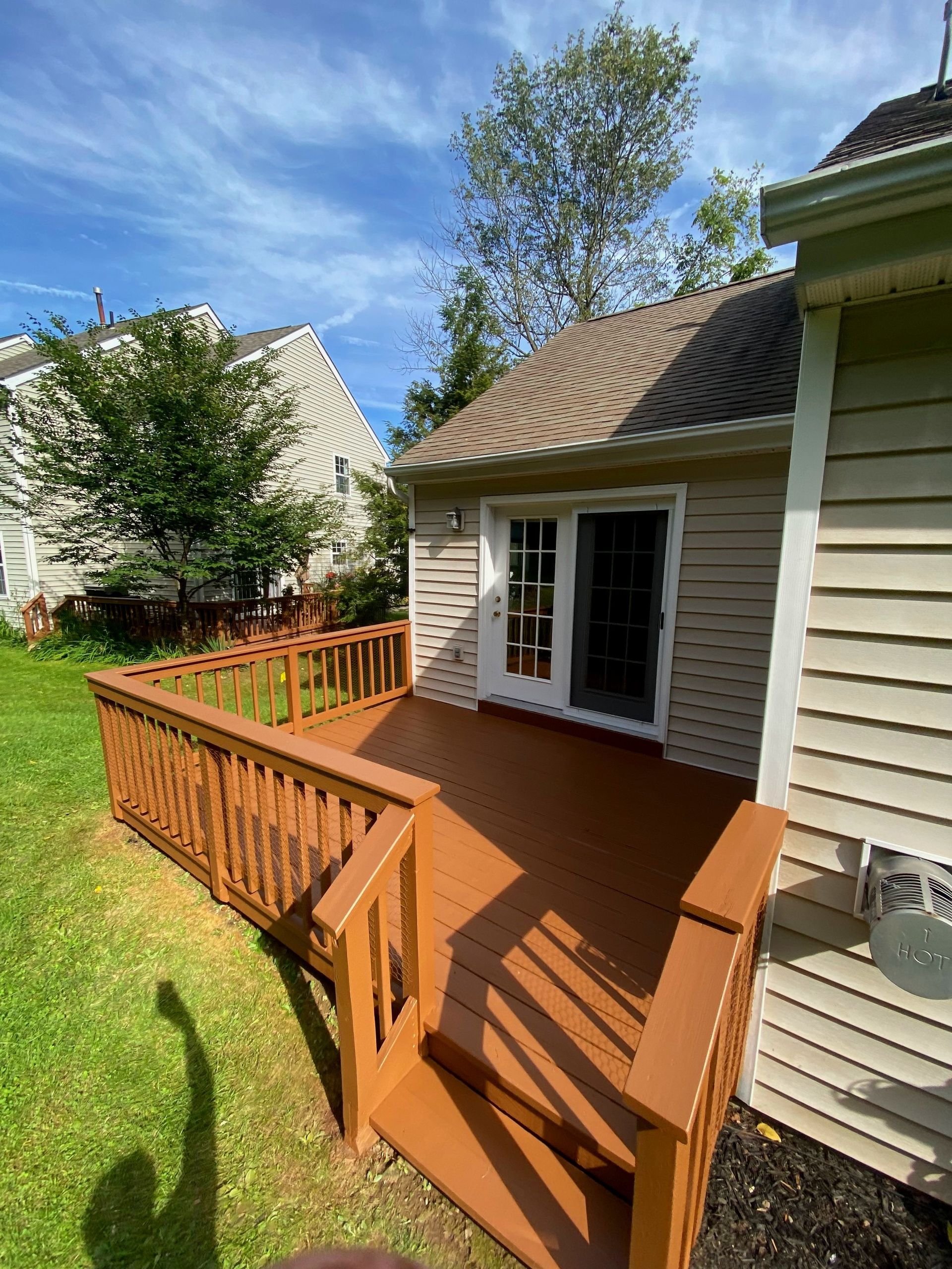 A wooden deck with stairs leading to the back of a house.