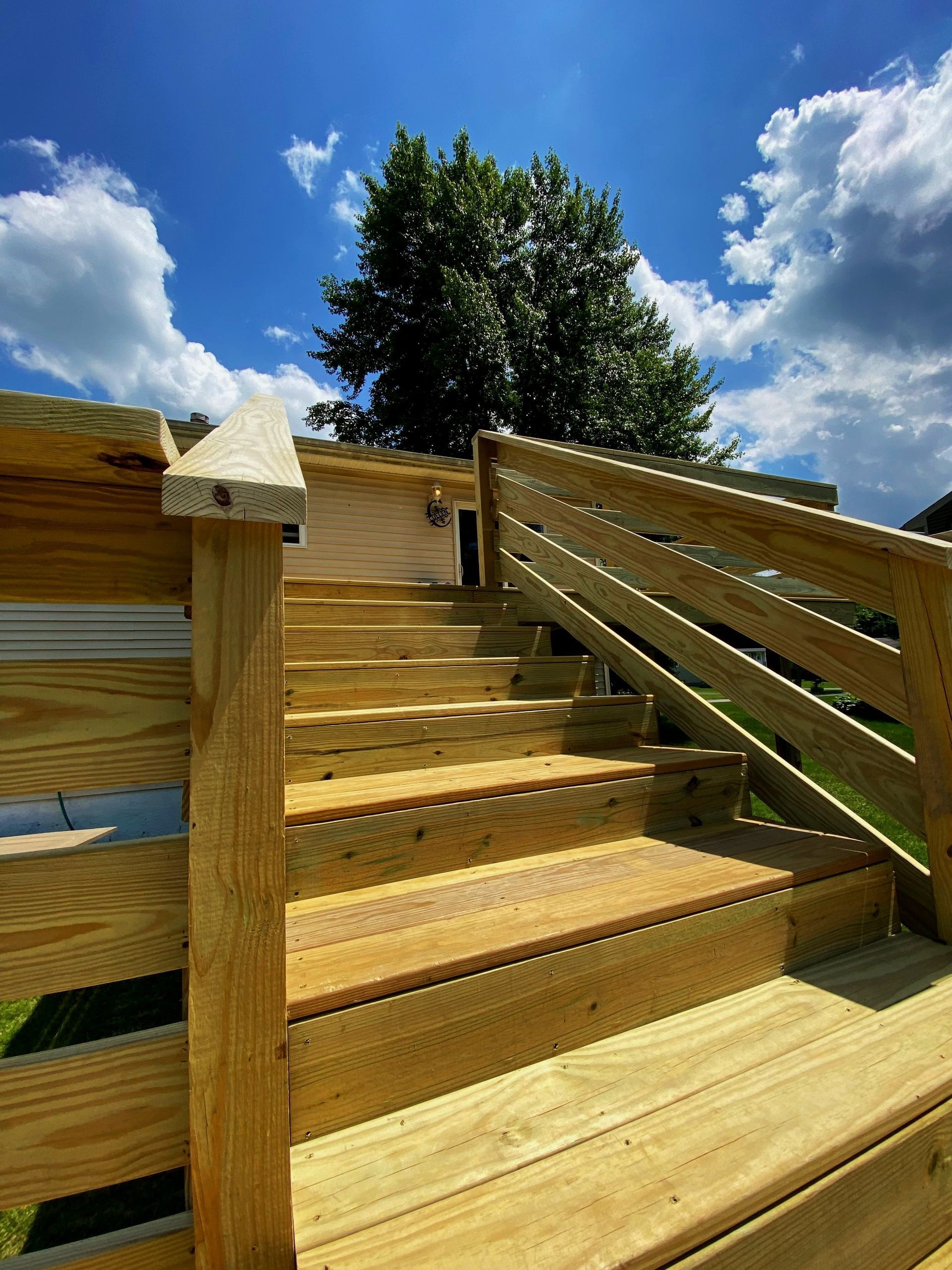 A wooden deck with stairs leading up to a house.