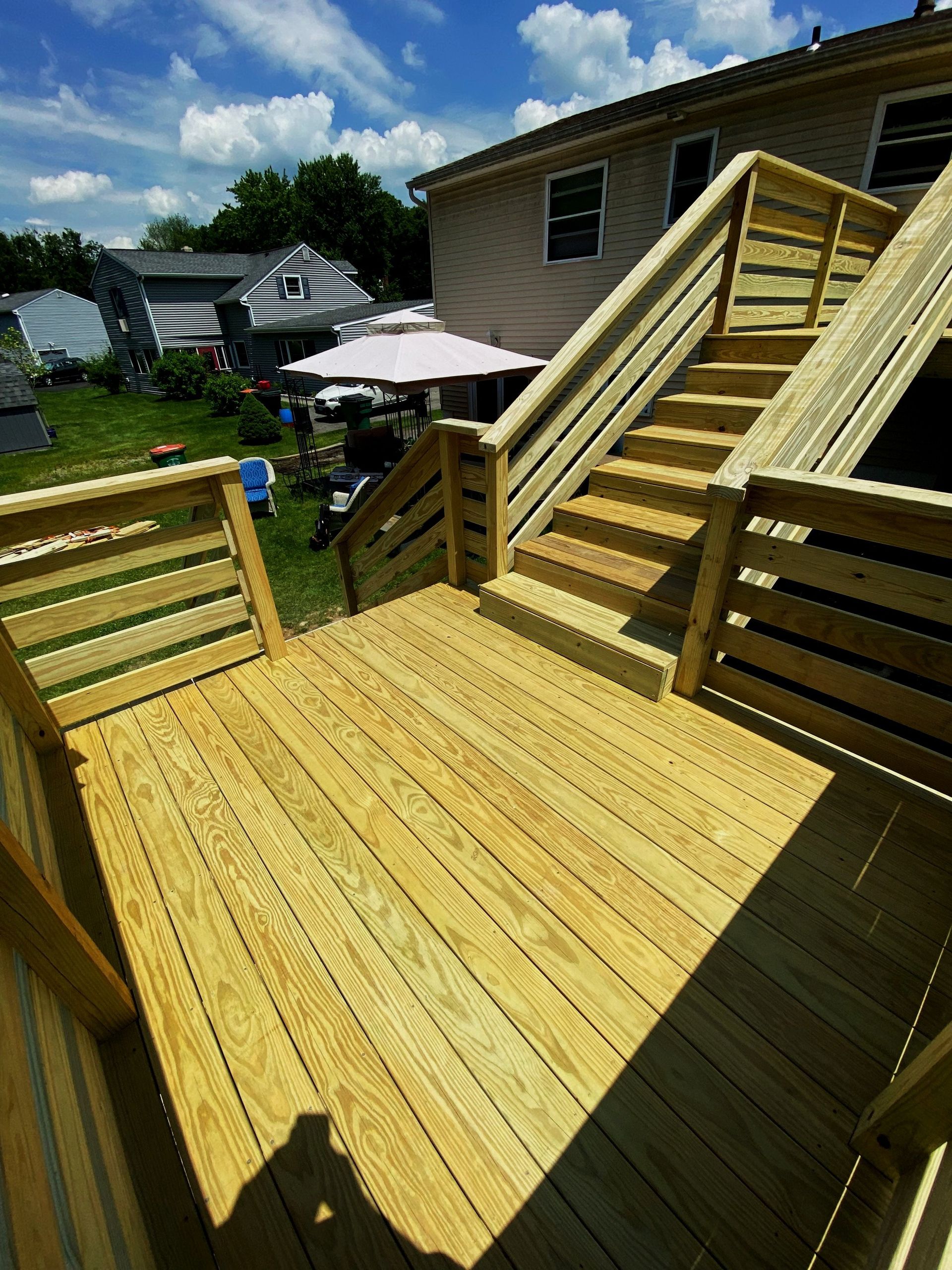 A wooden deck with stairs leading up to a house.