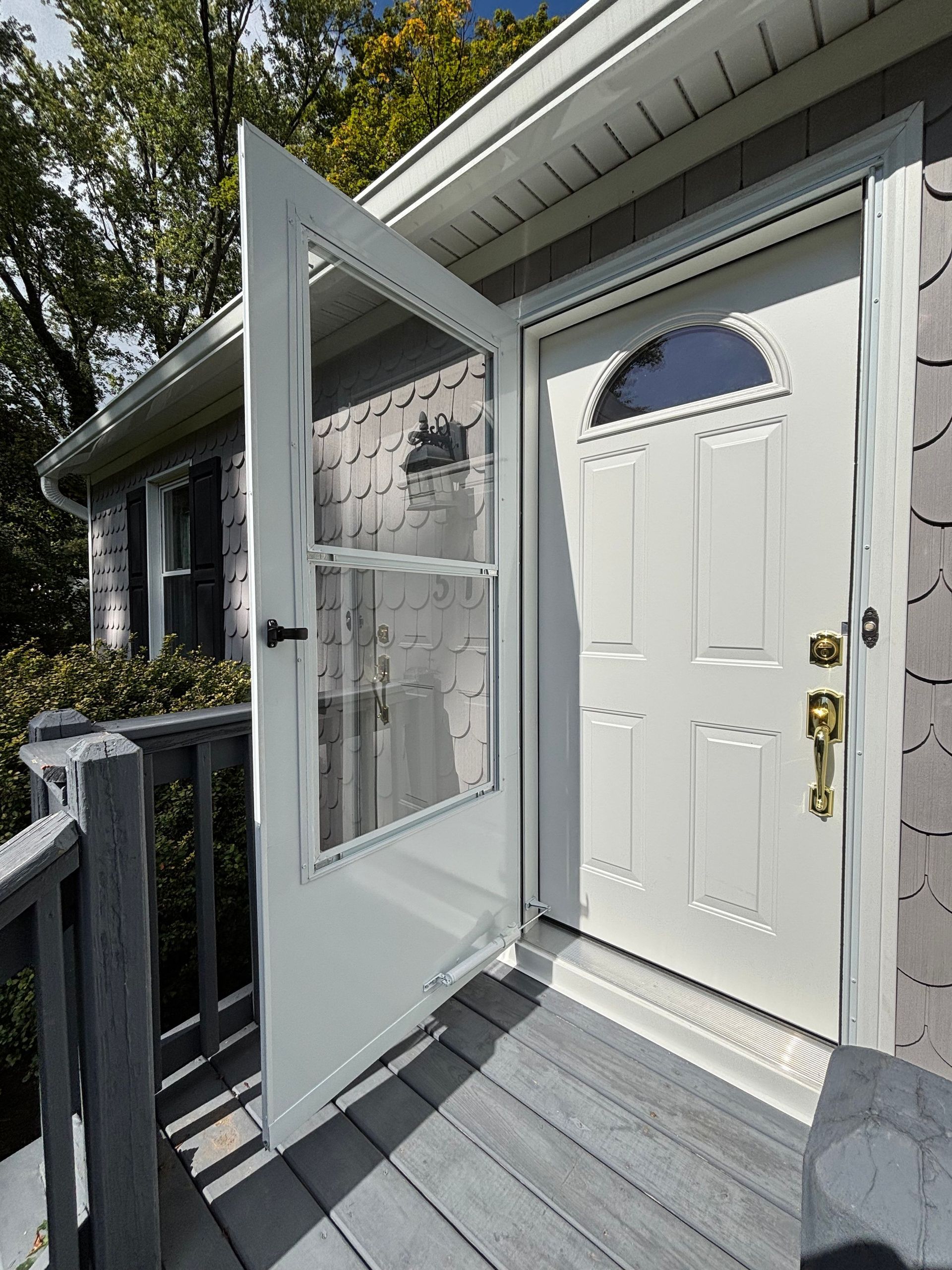The front door of a house is open to a deck.