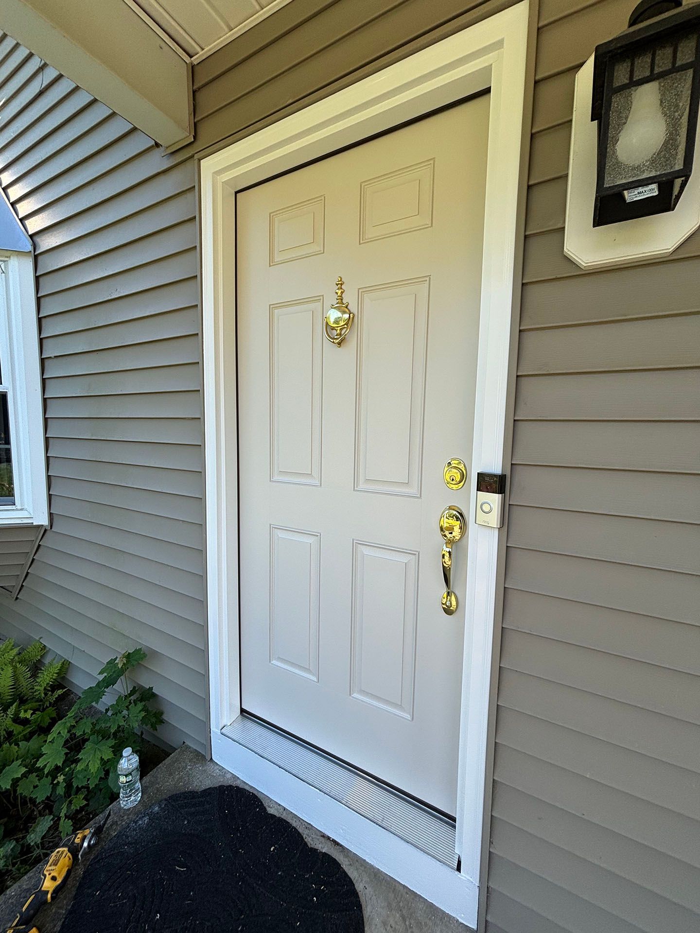 A white door with gold handles is on the side of a house.