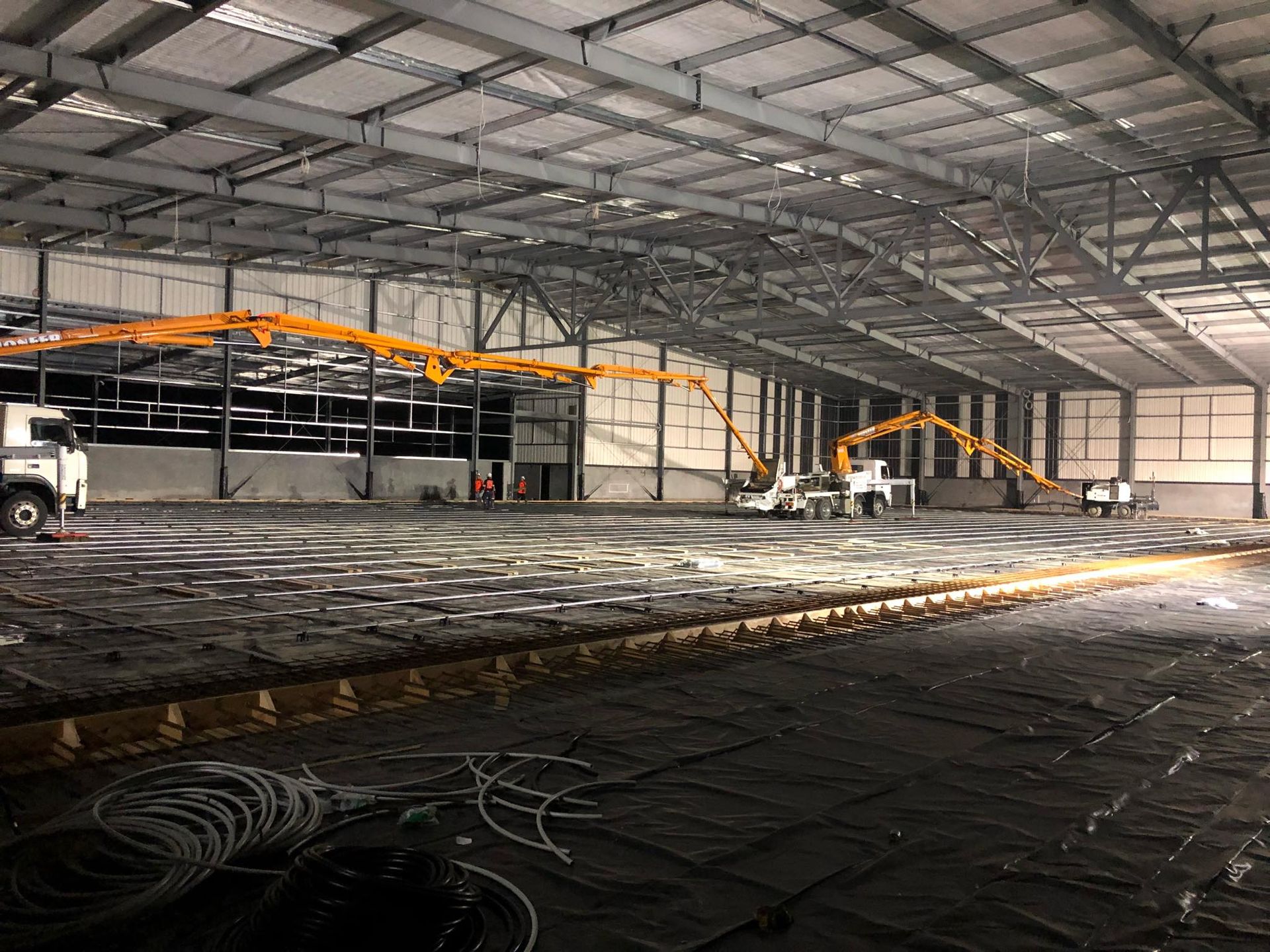 A large warehouse with a lot of concrete being poured into it.