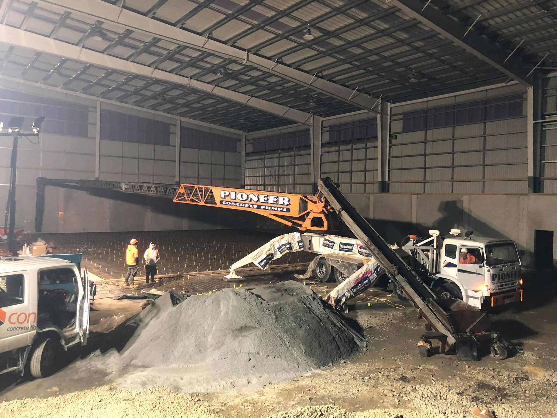 A large warehouse with a pile of dirt and a crane.