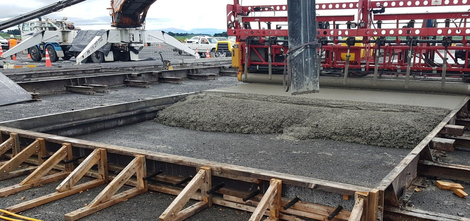 A large concrete slab is being poured into a wooden form.
