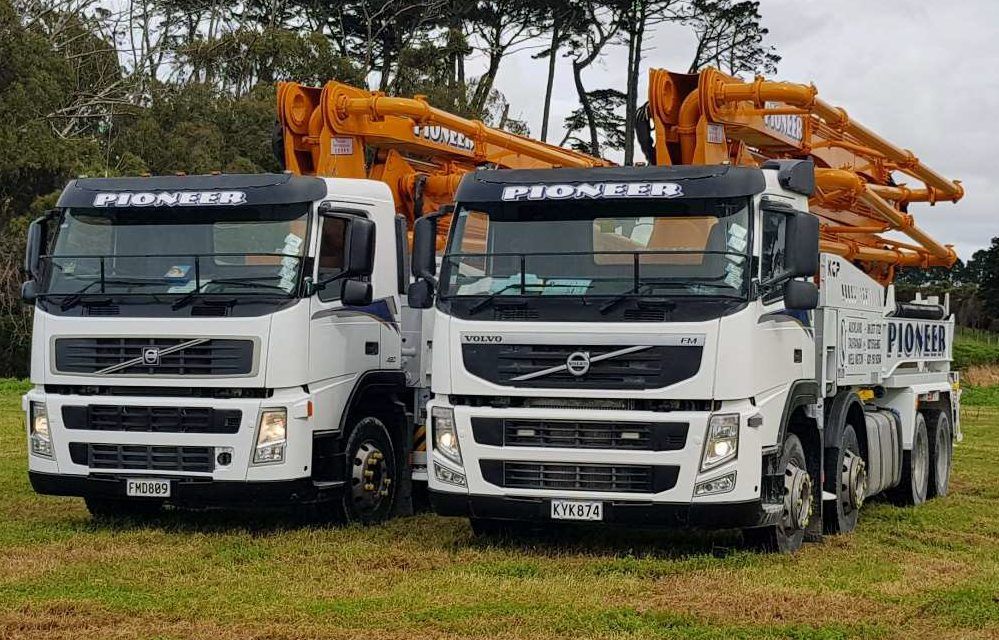 Two volvo trucks are parked next to each other in a grassy field.
