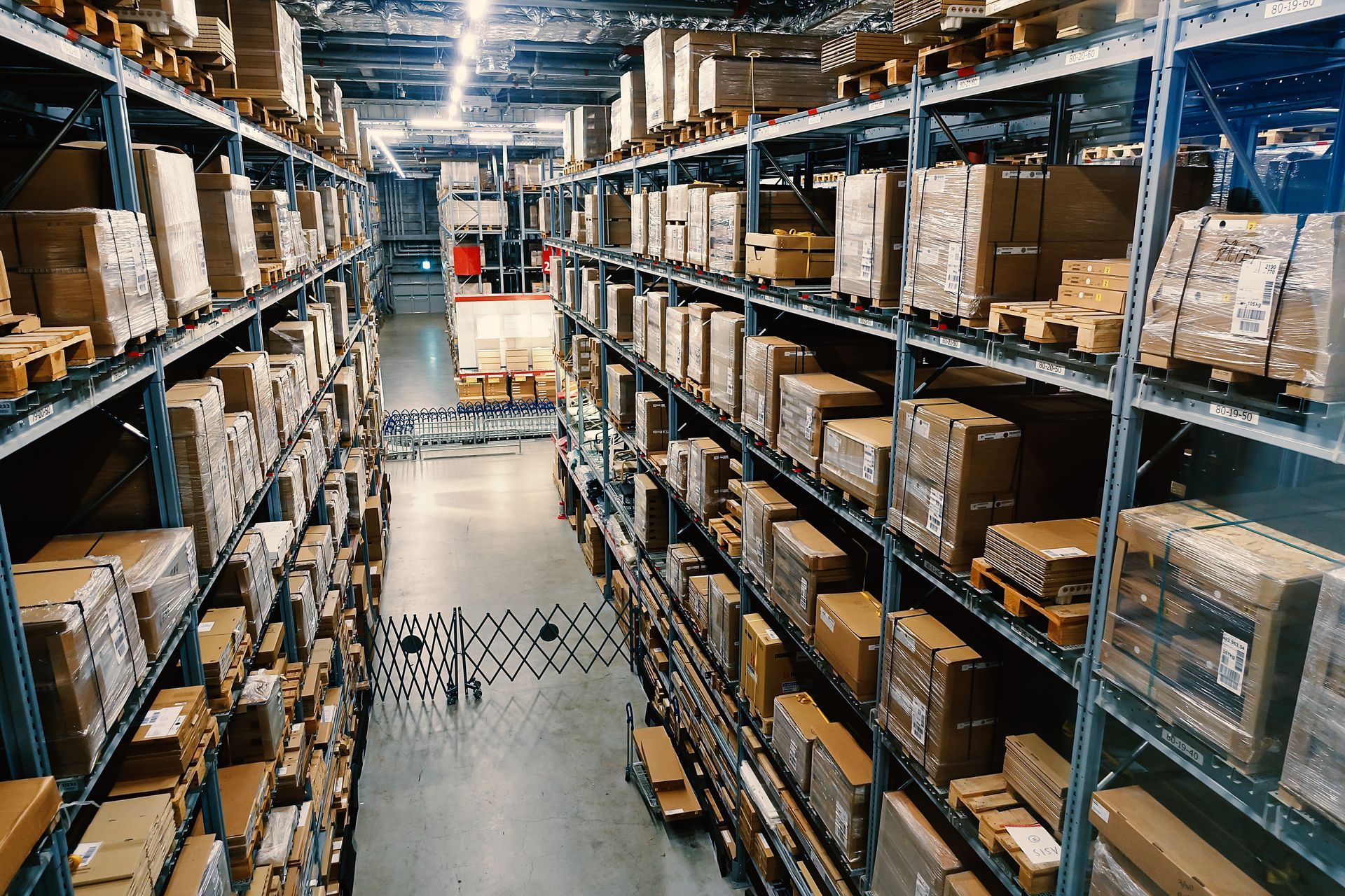 Warehouse interior with rows of shelves filled with cardboard boxes.