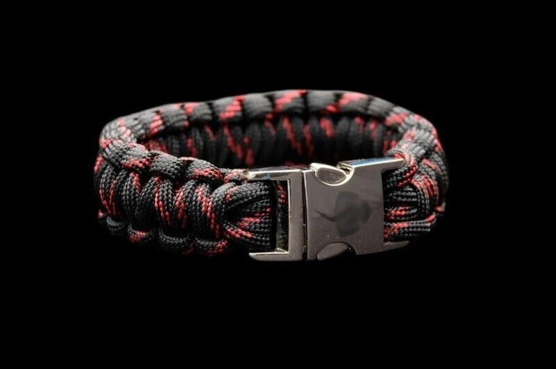 A black and red paracord bracelet with a silver buckle on a black background.