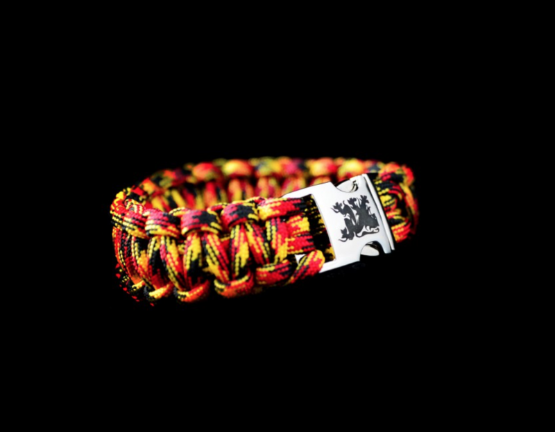 A colorful paracord bracelet with a silver buckle on a black background.