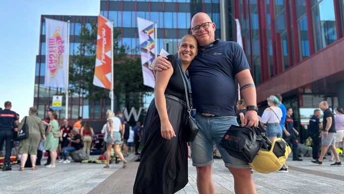 A man and a woman are posing for a picture in front of a crowd of people.