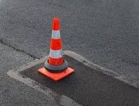 Orange and white traffic cone on dark asphalt