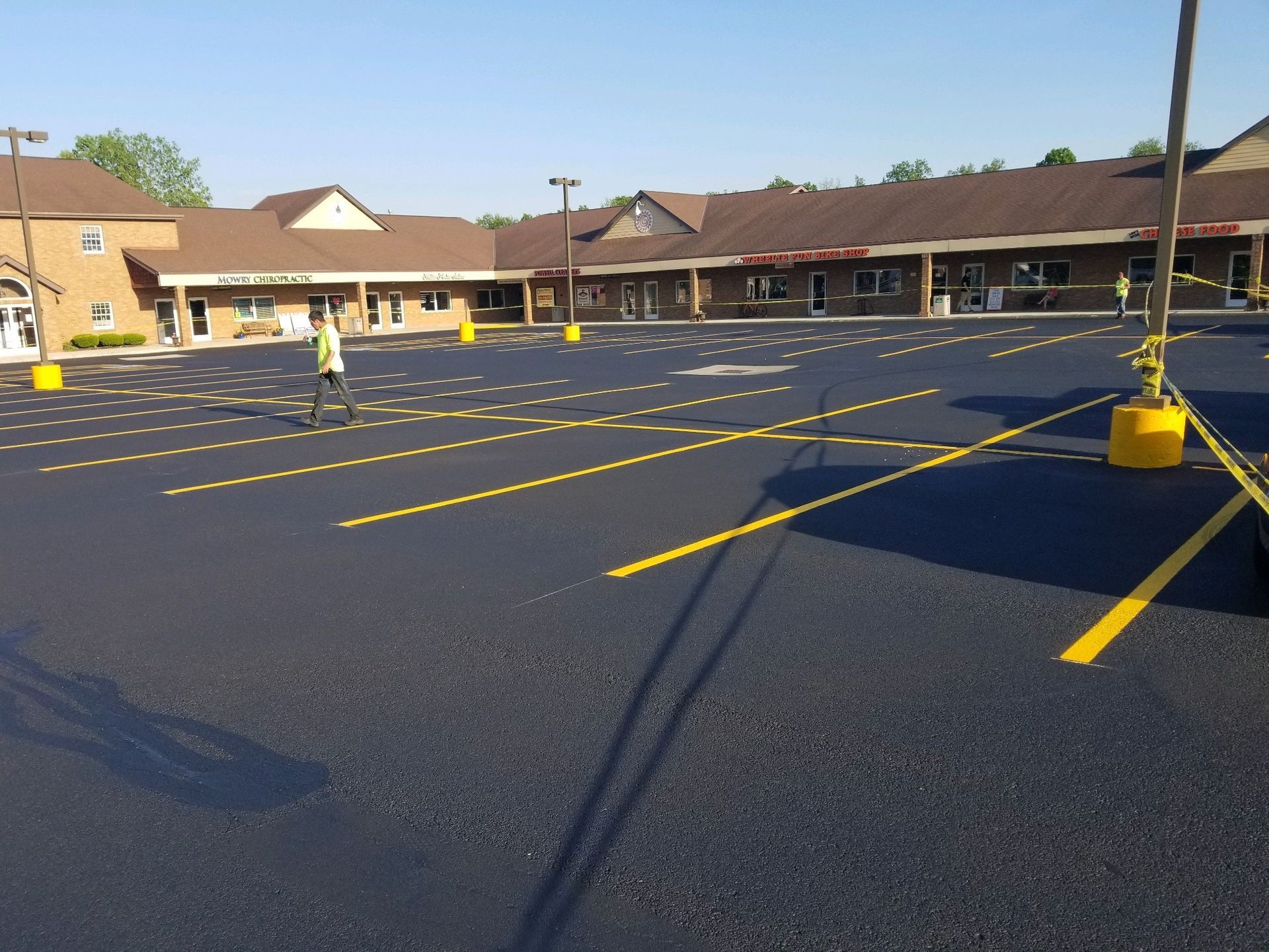 Freshly painted asphalt parking lot with yellow lines. A person in a vest stands in the lot.