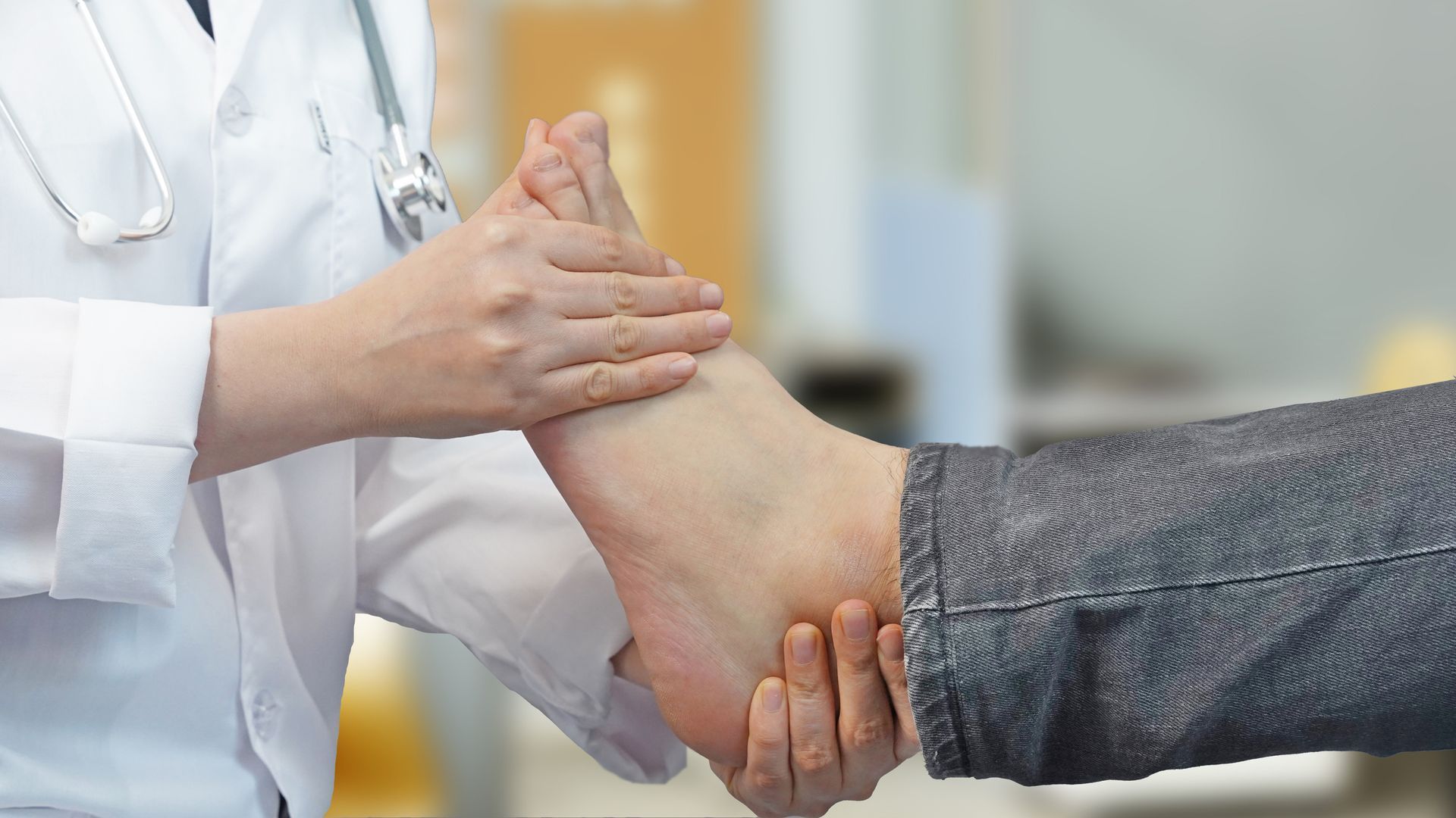 Foot doctor examining patient's leg and foot in clinic for diagnosis and treatment of foot pain.