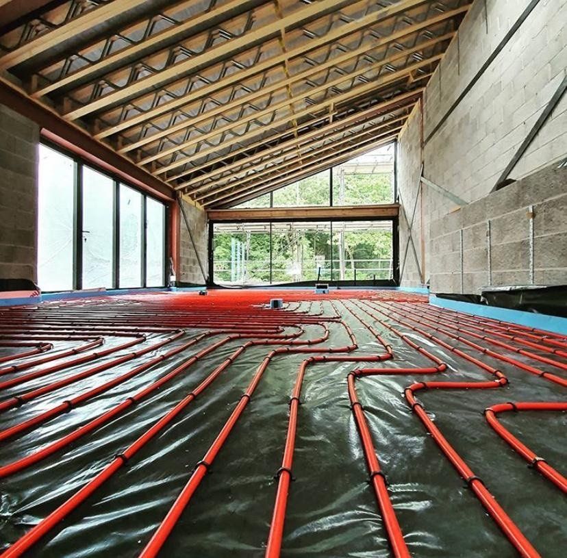 Red underfloor heating tubing exposed in large room