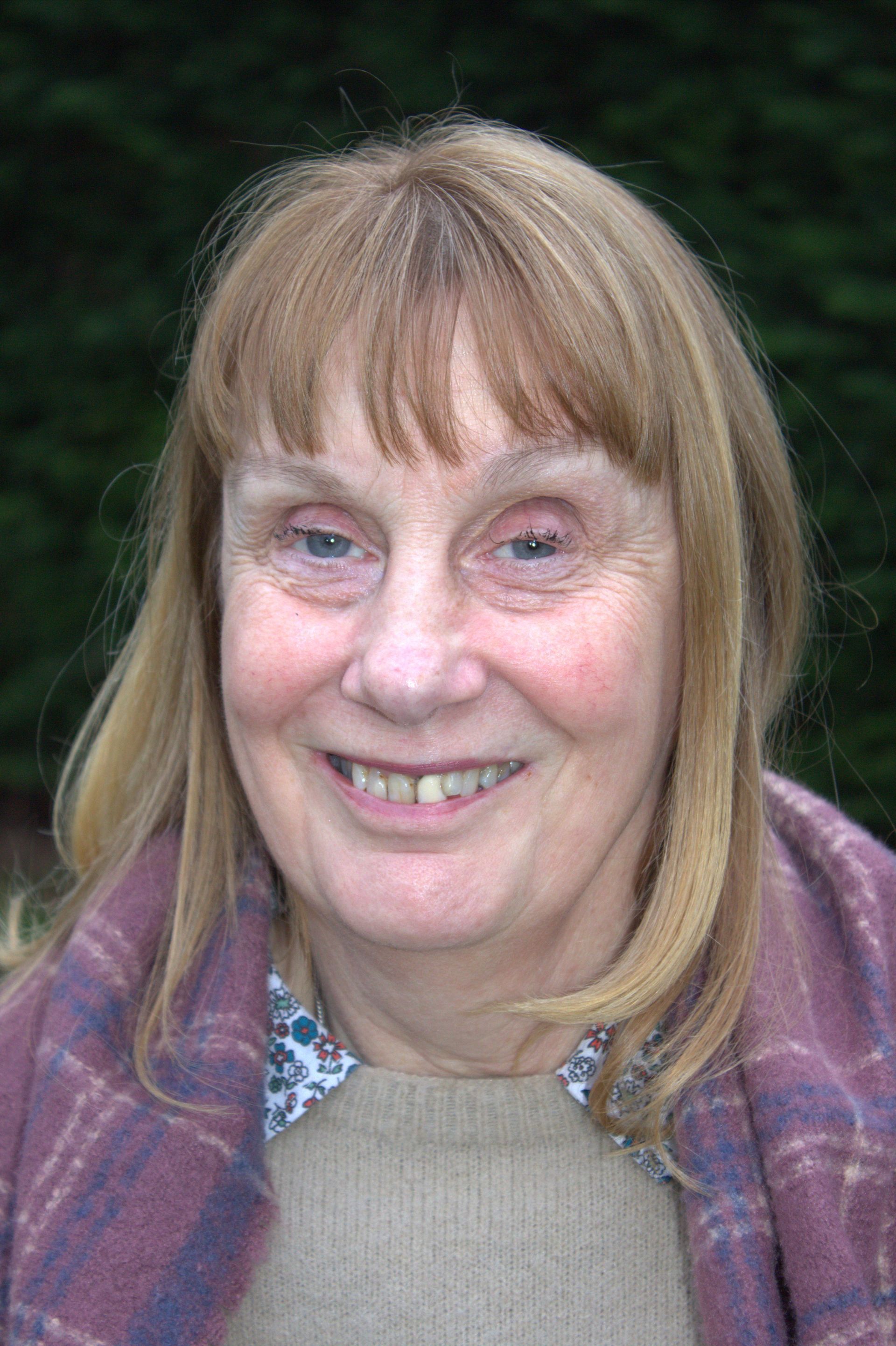 A close up of a woman wearing a scarf and smiling.