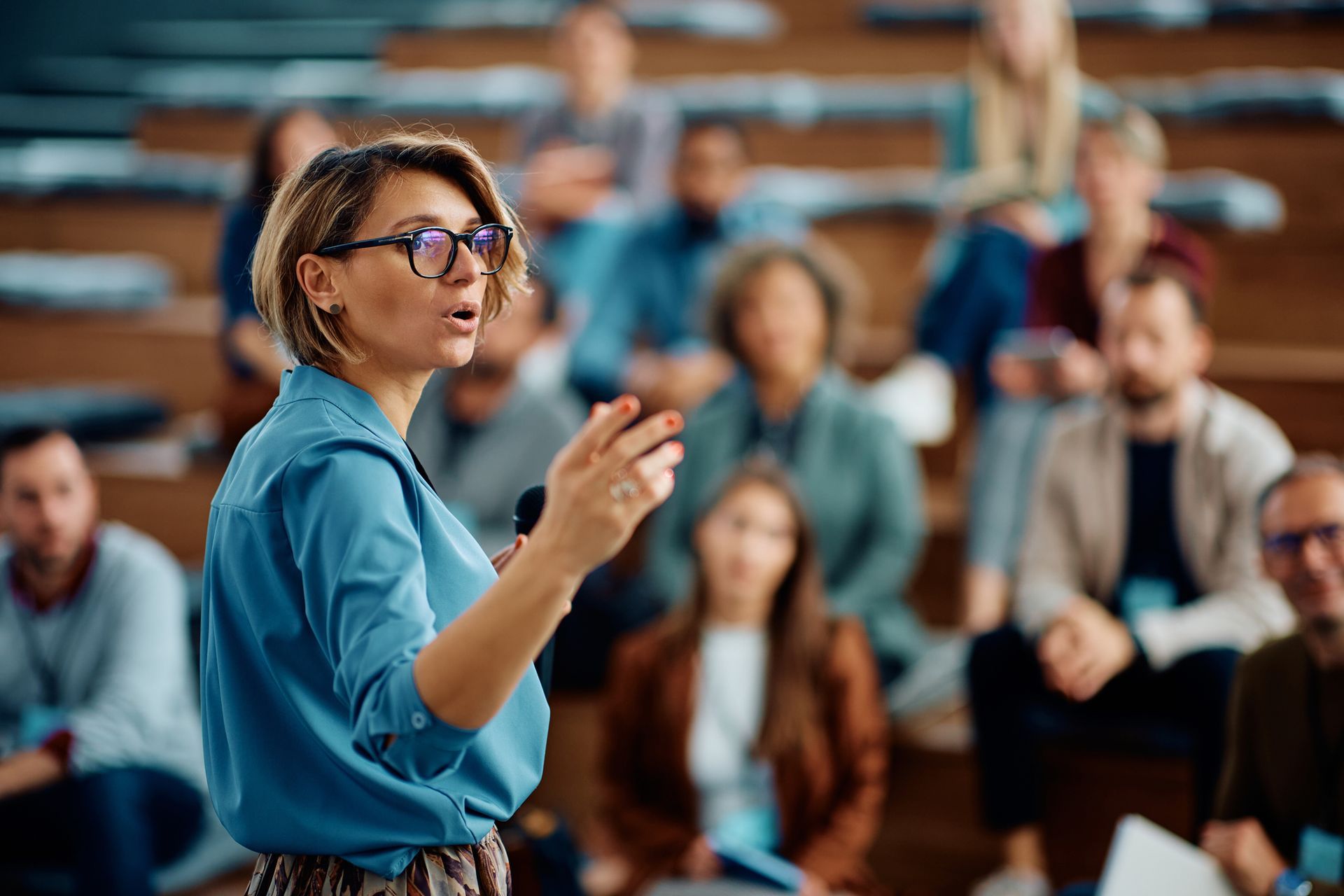 A woman is giving a presentation to a group of people in a lecture hall.
