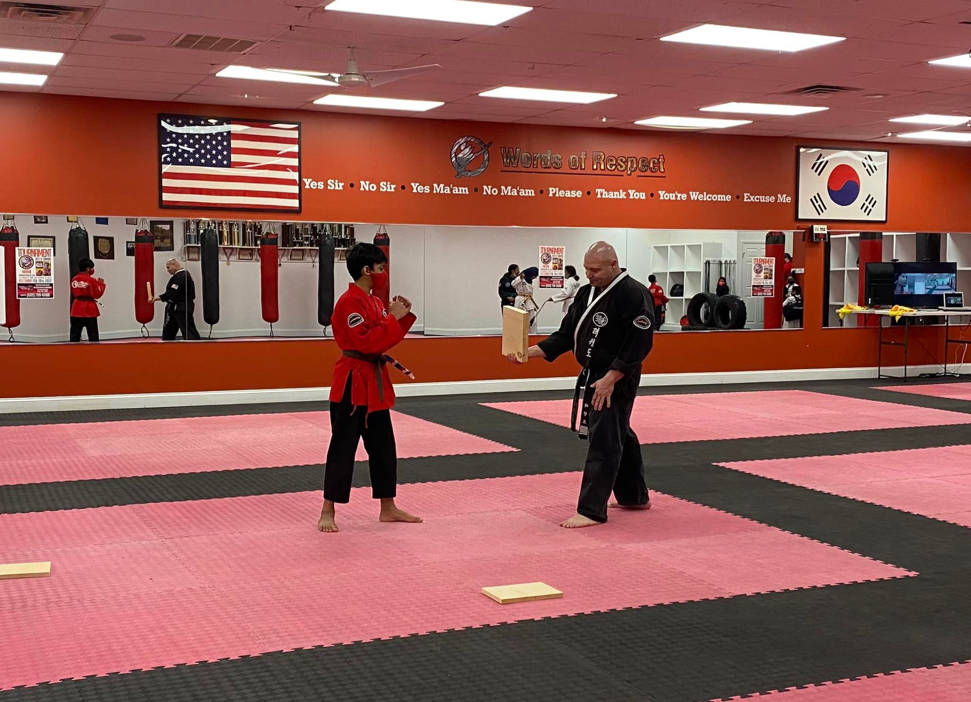 a man and a woman are practicing martial arts in a gym .