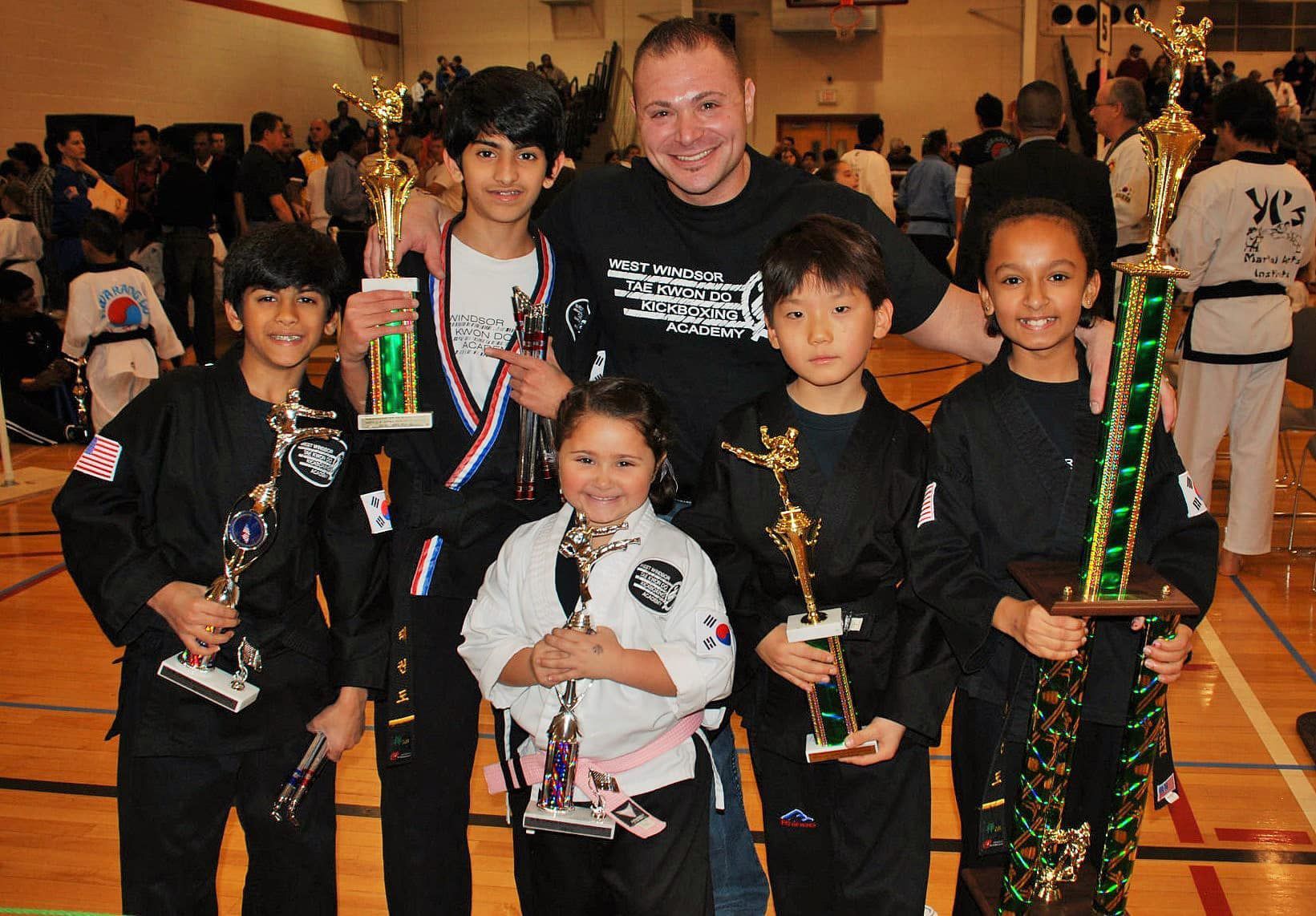 a group of kids are posing for a picture holding trophies