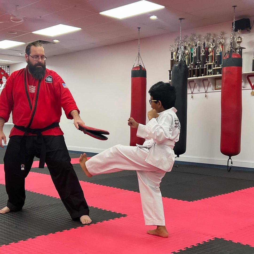 a man and a boy are practicing martial arts in a gym .
