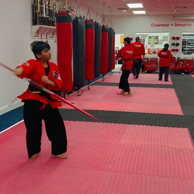 a group of people are practicing martial arts in a gym with a sign that says courtesy