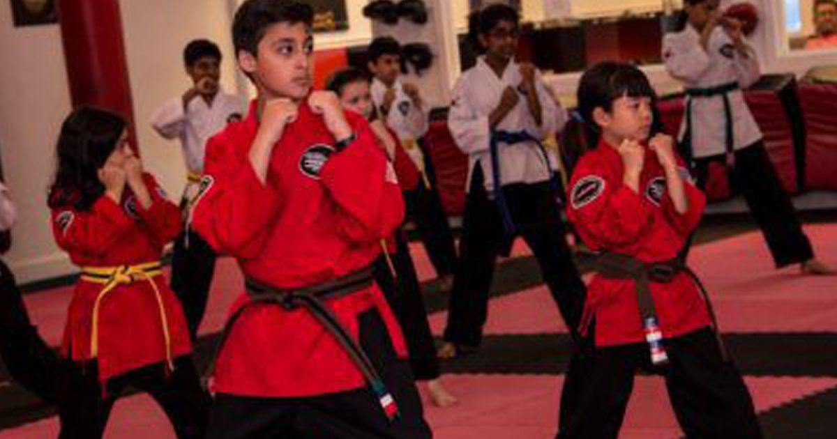 a group of children are practicing martial arts in a gym .