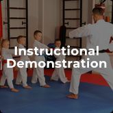 a group of children are practicing karate with a teacher in a gym .