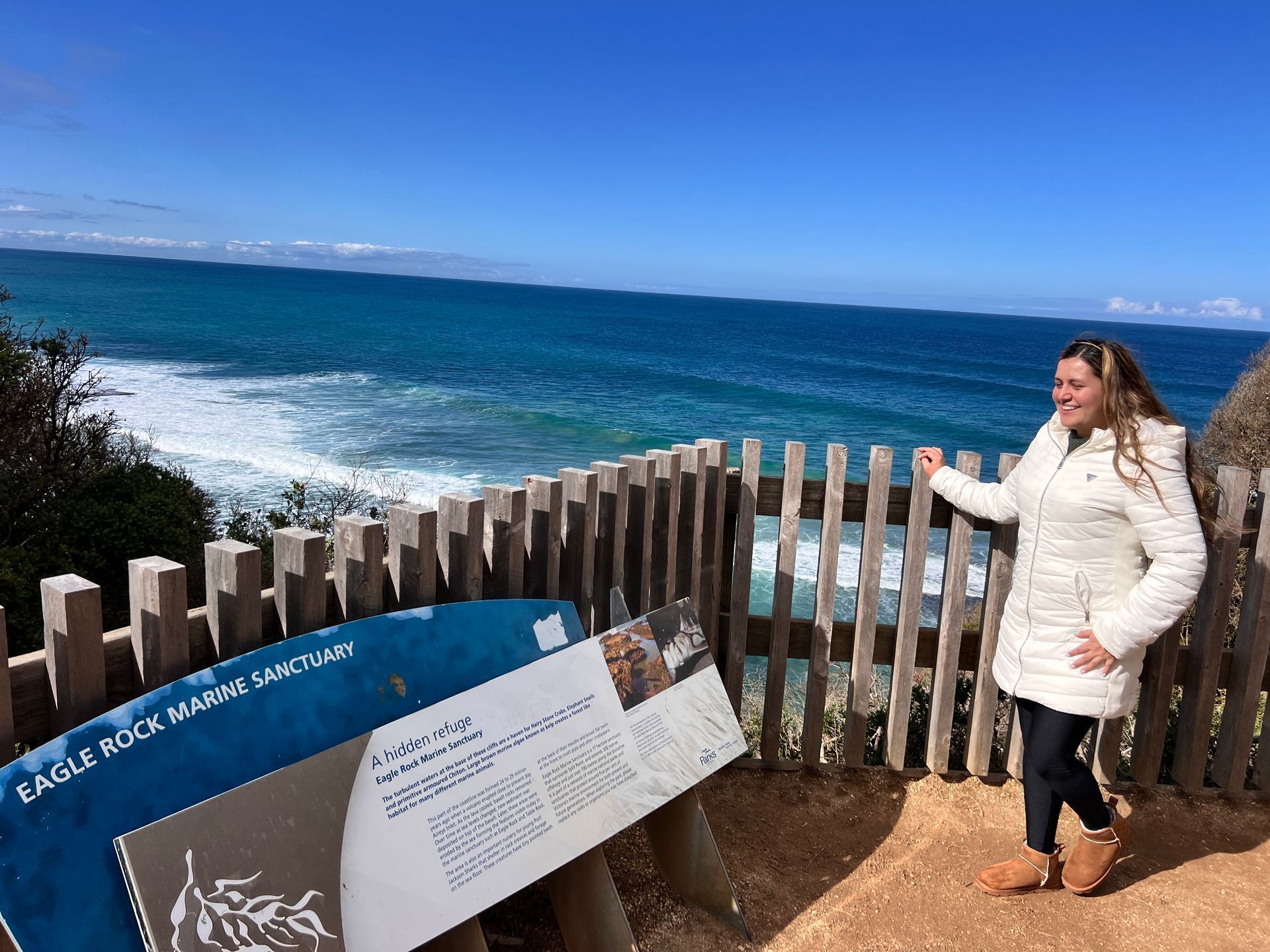 Pessoas andam de bicicleta em uma trilha de terra através de um cânion com formações rochosas vermelhas e folhagens verdes.