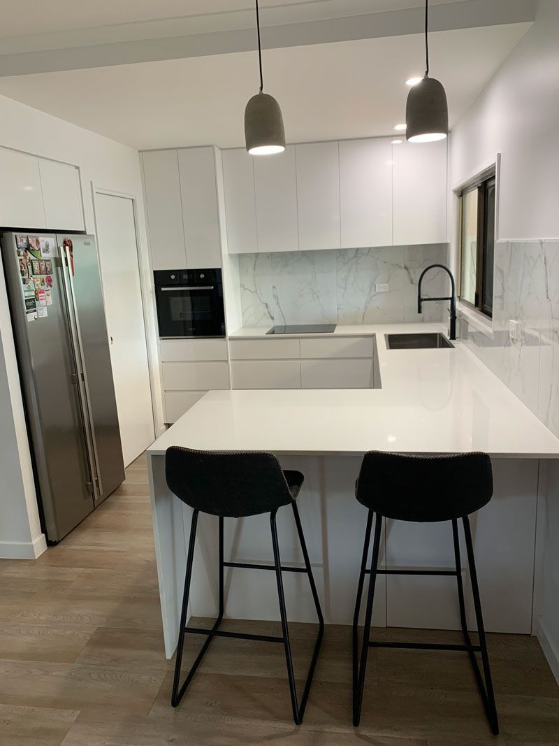 Two chairs and fridge in white kitchen — Cabinetry in Cairns, QLD