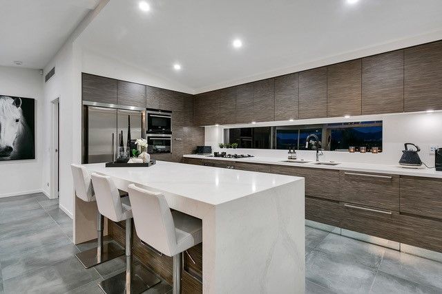 Kitchen with white chairs and brown cabinet — Cabinetry in Cairns, QLD