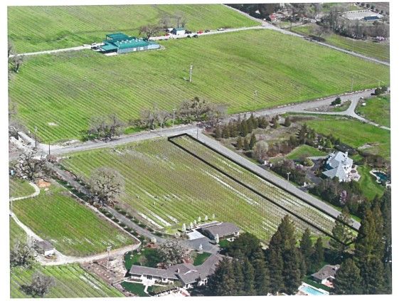 Aerial view of vineyard property. Rows of grape vines, road, and buildings. Outlined plot.