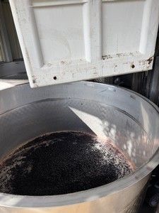 Large metal container holding a dark liquid and a white lid.
