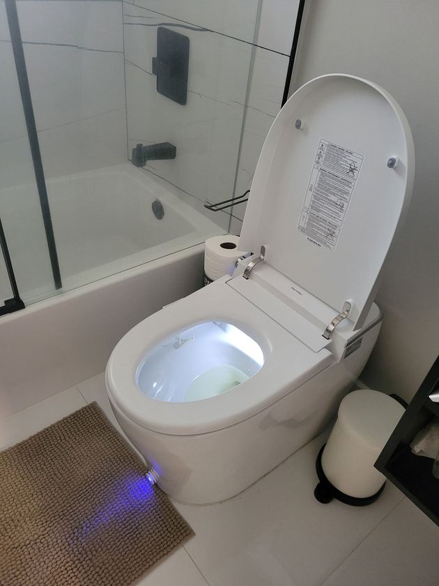 Gloved hand cleaning a dirty bathroom sink drain with a brush