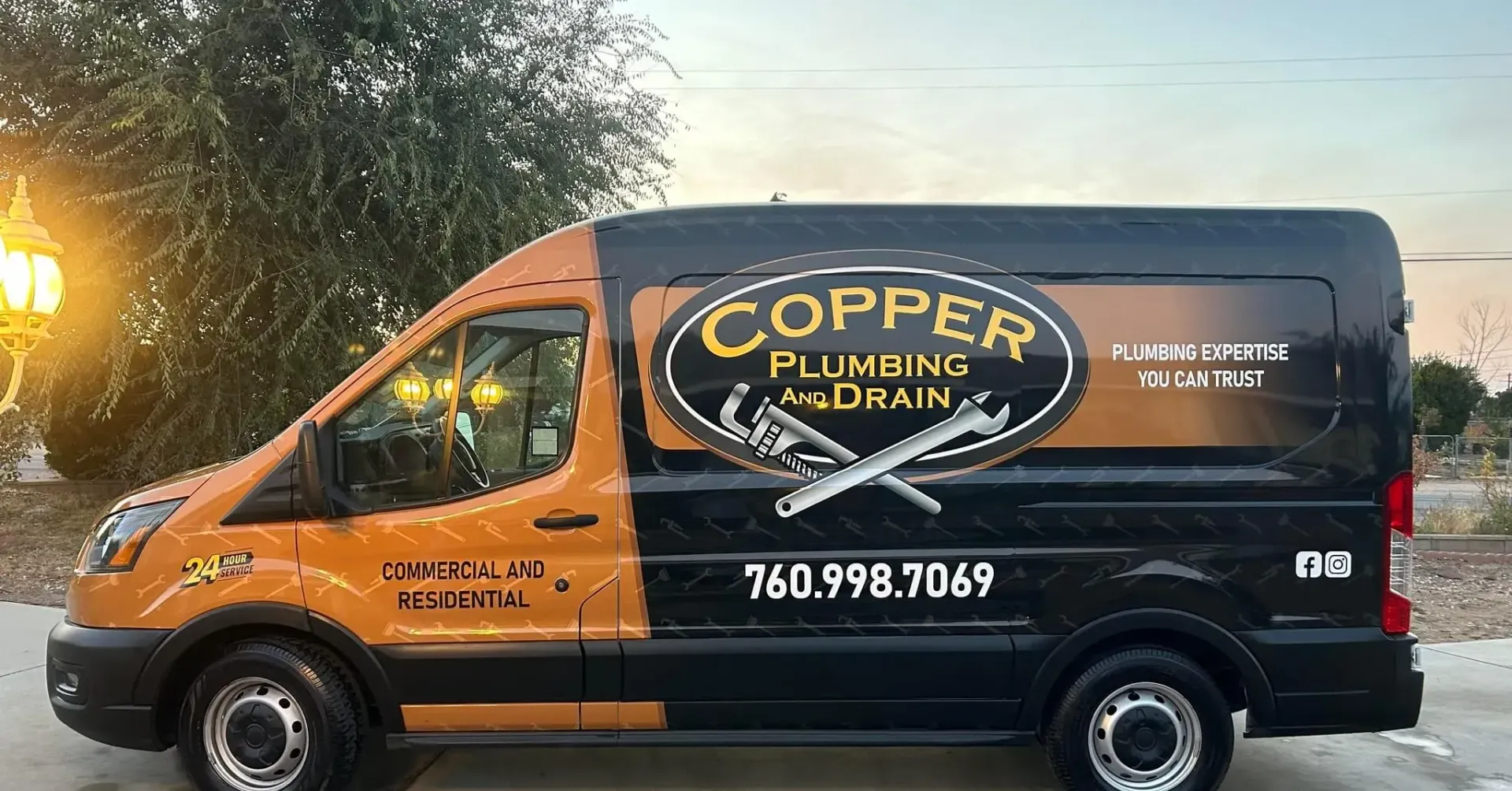 Orange-and-black Copper Dream plumbing van parked roadside at dusk
