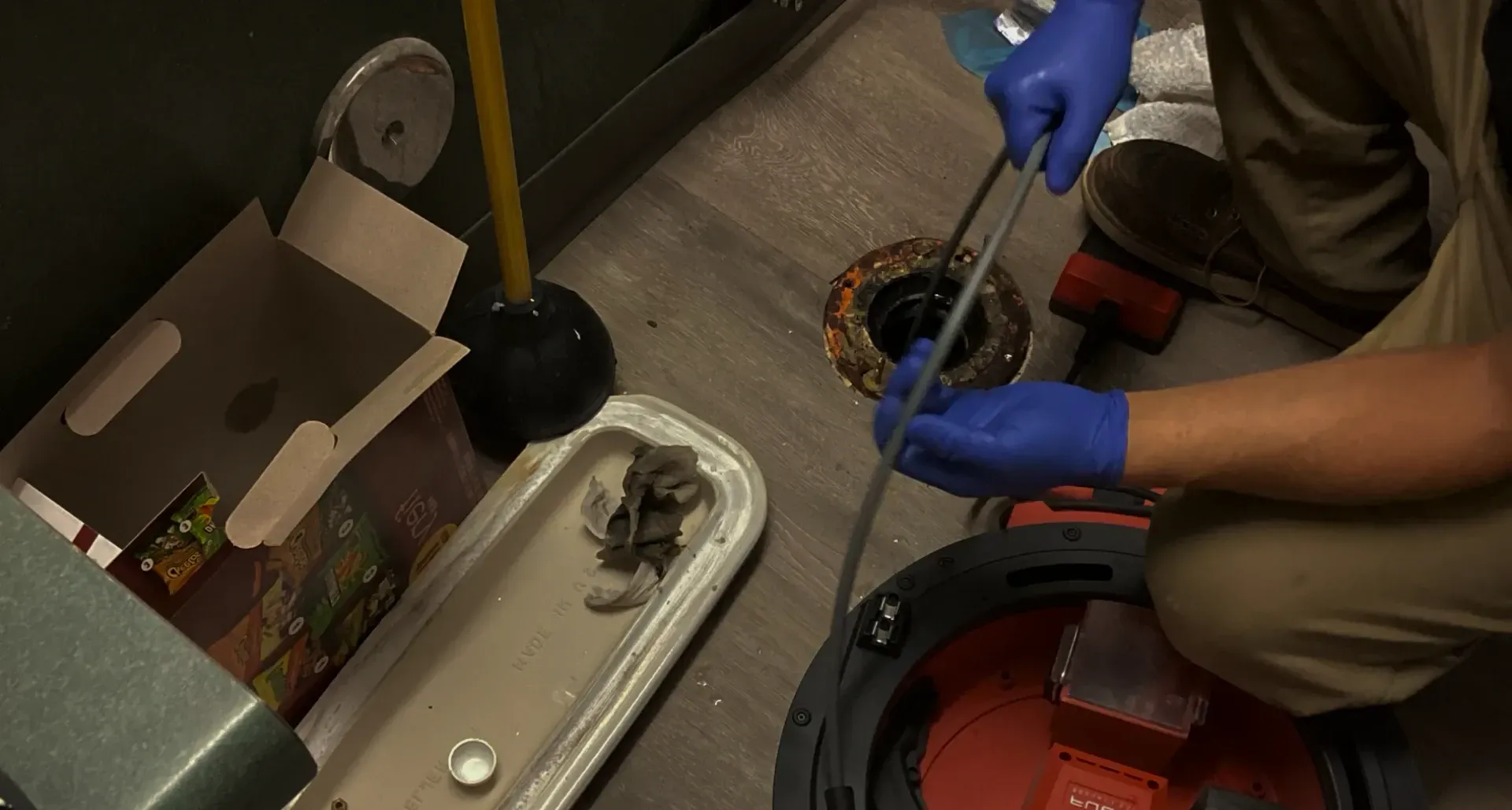 Gloved worker using tools to drain or repair a machine in a workshop area