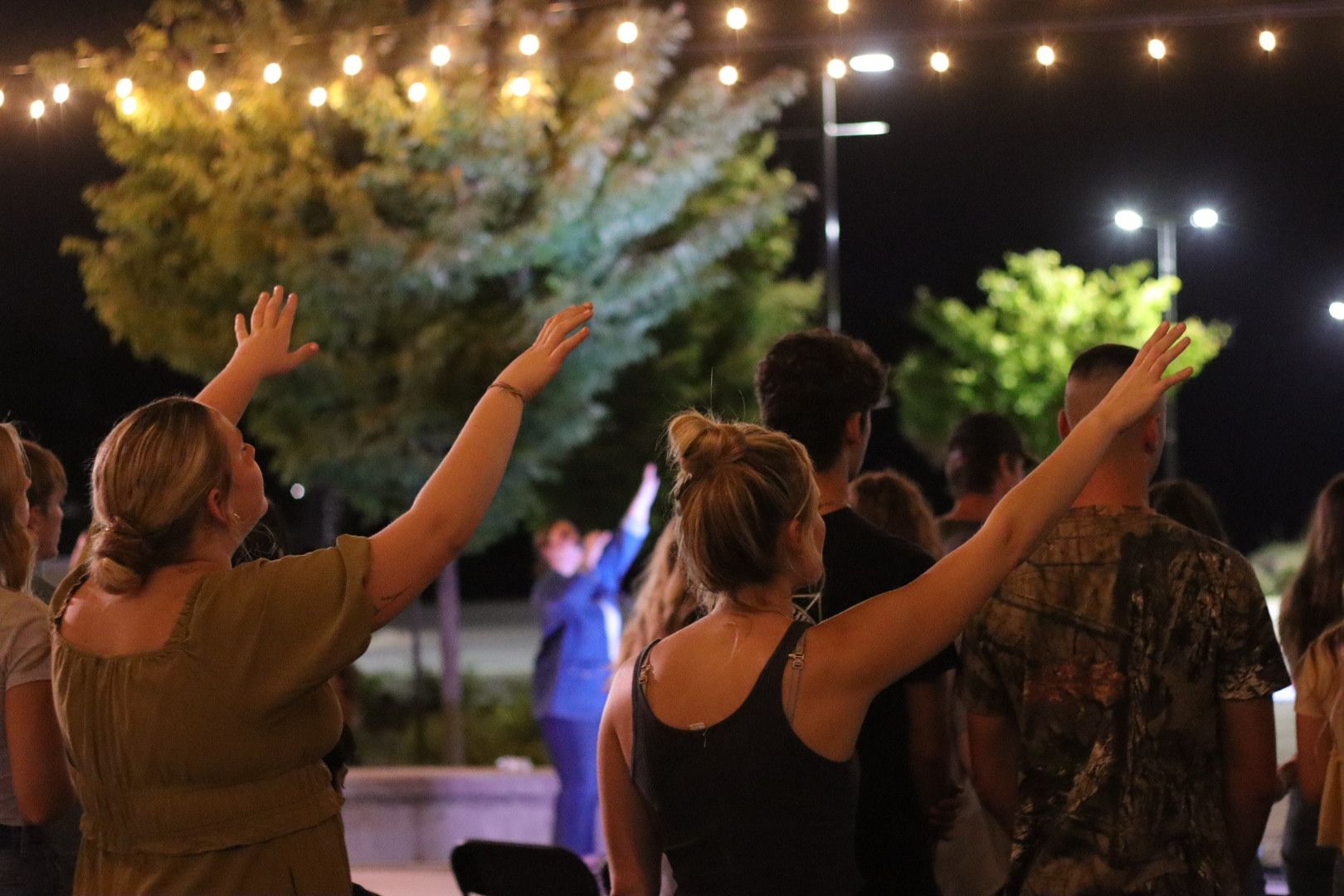 A group of people are standing in a circle with their arms in the air.