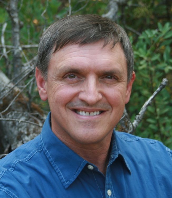 A man in a blue shirt is smiling for the camera