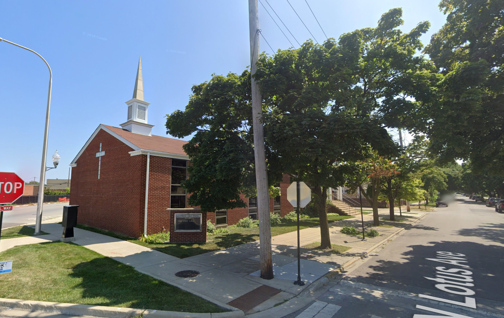 A stop sign is on the side of the road in front of a church
