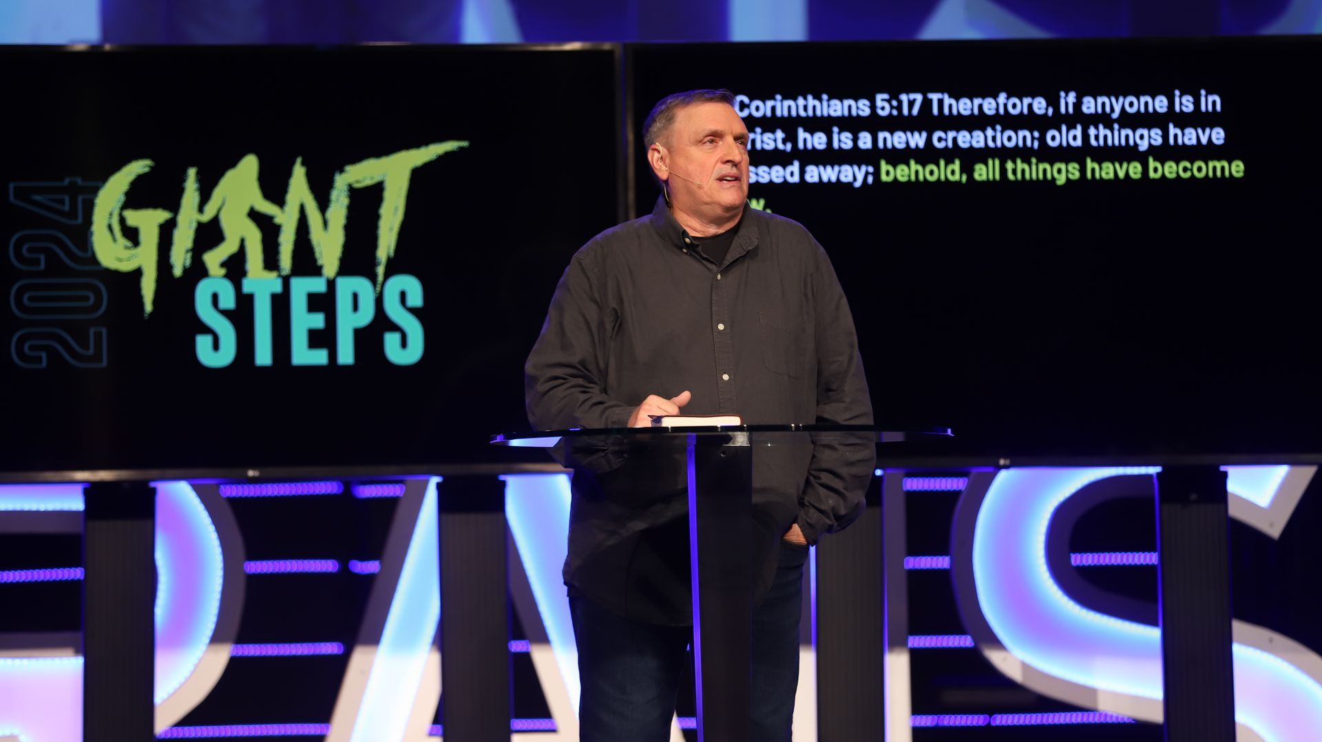 A man is standing in front of a giant steps sign